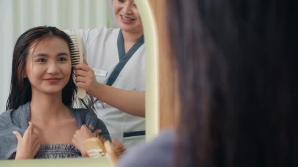 ビューティーサロンでミラーの前に若い女性クライアントの美容師のコメディショットと吹き飛ばしの乾いた髪 — ストック動画