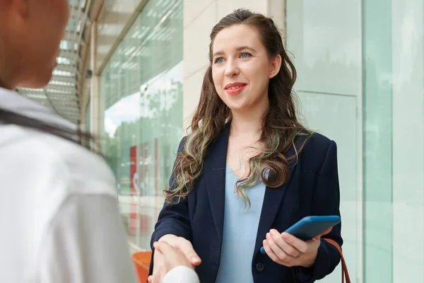 Lächelnde Junge Geschäftsfrau Mit Smartphone Schüttelt Geschäftspartner Die Hand — Stockfoto