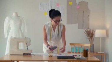 Atölyede çalışırken gelinlik dikmek için elbise seçerken orta boy terzi pozu.