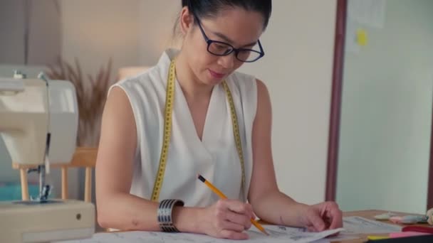 亚洲裁缝师为客户绘制时尚草图并看着相机的形象 — 图库视频影像