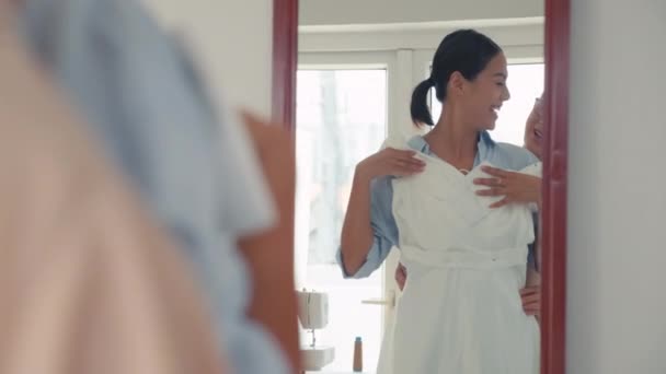 アトリエの母親と一緒に鏡の前でウェディングドレスを試す陽気な花嫁のミディアムロングショット — ストック動画