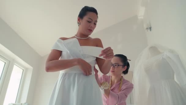 アトリエにフィッティングで花嫁のウェディングドレスをチェックする縫い目感の低い角度ビュー — ストック動画