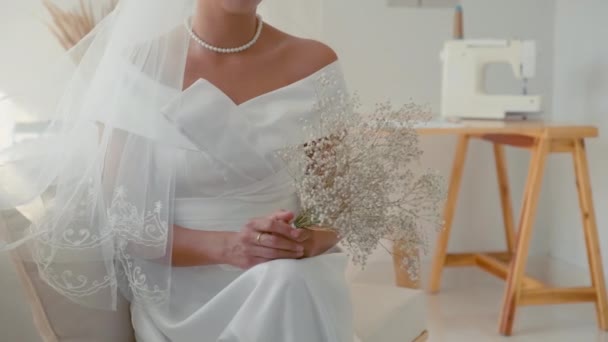 Gelinlik Giymiş Bir Gelin Elinde Çiçeklerle Kanepede Oturuyor — Stok video