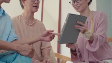 Gelinin ve annesinin dijital tablette oturan gelinlik fotoğraflarını gösteren terziyi yukarı kaldır.