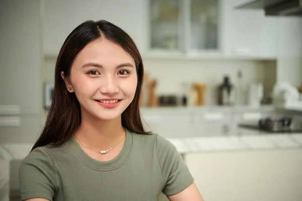 穿着T恤衫站在厨房里的快乐的年轻亚洲女人的画像 — 图库照片