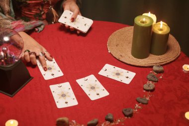 Geleceği tahmin ederken tarot kartları üzerinde el ele tutuşan kahinin yakın plan resmi