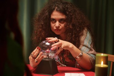 Gizemli medyum kristal küreye bakıyor ve müşteriyle konuşuyor.