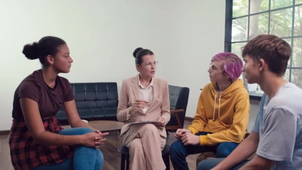 グループコンサルテーションで心理学者を聴く多民族のティーンエイジャーのワイドショット — ストック動画