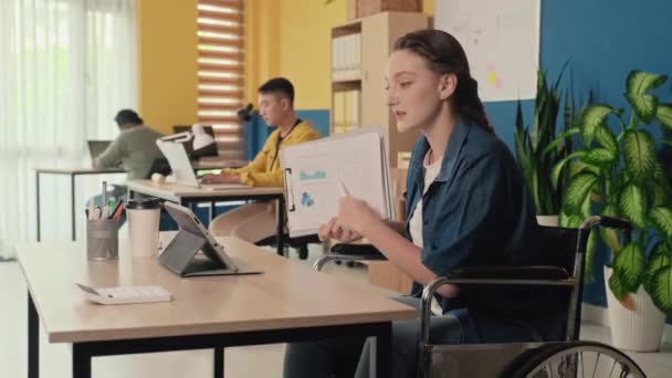 坐在轮椅上的年轻女性在办公室数码平板电脑上对商业伙伴进行视频定位 — 图库视频影像