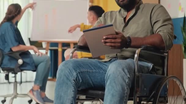 Tekerlekli Sandalyedeki Gülümseyen Genç Işadamının Yerinde Kameraya Bakarak Notlar Alırken — Stok video