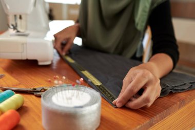 Müşteri için önlük üzerinde çalışırken mezura kullanan terzi