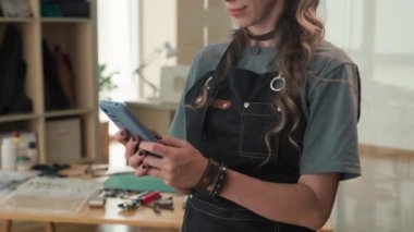 Deri ustasının atölyede akıllı telefondan müşteriyle konuşurken çekilen görüntüsü.