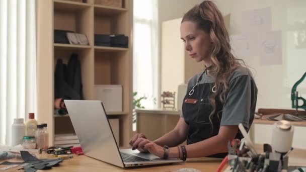 Deri Atölyesinde Dizüstü Bilgisayarla Çalışan Genç Bir Kadının Orta Boy — Stok video