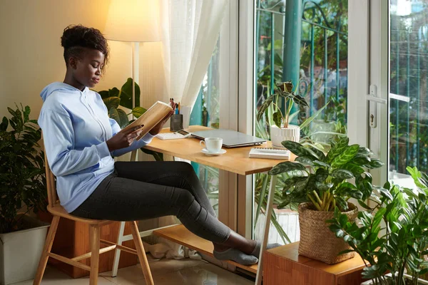 Černá Žena Sedí Stolem Své Domácí Kanceláři Čtení Knihy — Stock fotografie