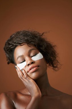 Siyahi kadın serin göz bantlarının keyfini çıkarıyor.