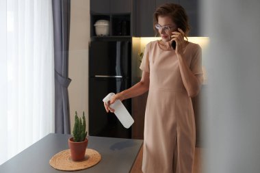 Telefonda konuşurken kaktüs sıkan, gülümseyen, zarif bir kadın.