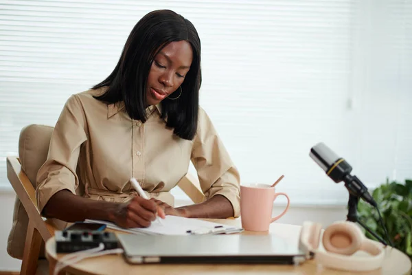 エレガントな黒人女性コーヒーを飲んでポッドキャスト用スクリプトに取り組む — ストック写真