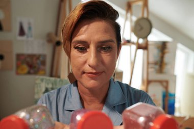 Düşünceli yaratıcı olgun kadın işi için resim rengini seçiyor.