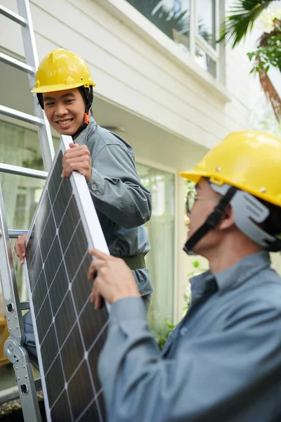 家の屋根の太陽電池パネルを持ち上げる請負業者 — ストック写真