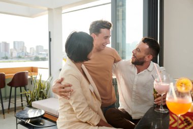 Mutlu genç adam, çatıdaki barda vakit geçirirken en iyi arkadaşlarına sarılıyor.