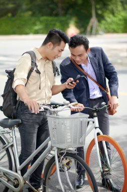Genç Asyalı iş adamı yeni cep telefonu uygulaması veya akıllı telefondan meslektaşına ilginç bir video gösteriyor