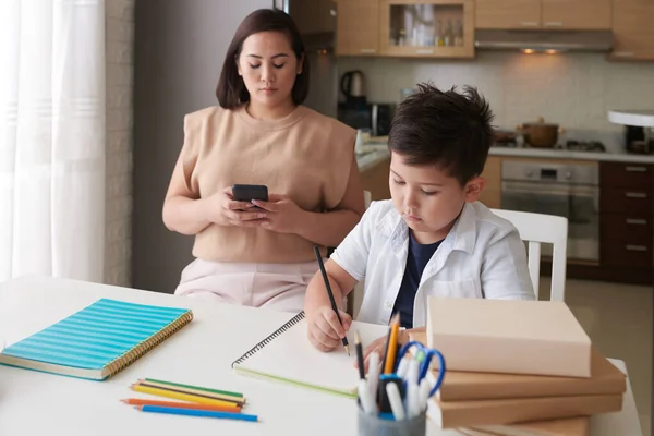 Concentrated Little Boy Doing Homework Control His Mother — Stock Photo, Image
