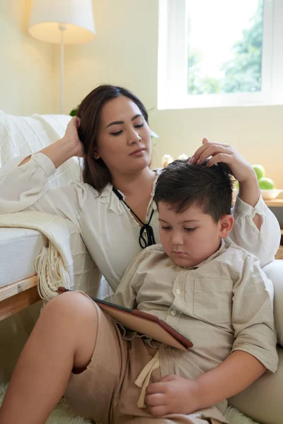 タブレットコンピュータの本を読む上でゲームをしている息子の母シャッフルの髪 — ストック写真