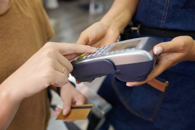 Saç kesimi için kredi kartıyla ödeme yaparken, müşterinin elleri pin kodunu giriyor
