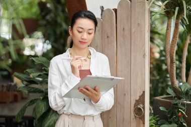 Genç Asyalı iş kadınının portresi dokümanı panoya dolduruyor