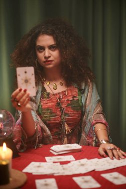 Ciddi falcının portresi tarot kartı gösteriyor, uyarı istemcisi