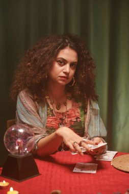 Ciddi bir büyücü tarot kartları karıştırıyor ve önünde yayılıyor.