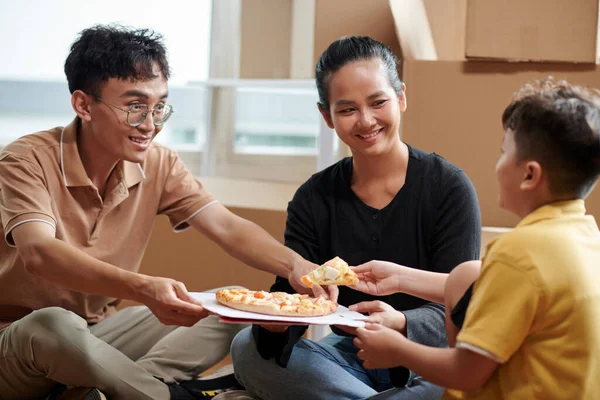 新しいアパートでピザを食べる幸せなアジアの家族 — ストック写真