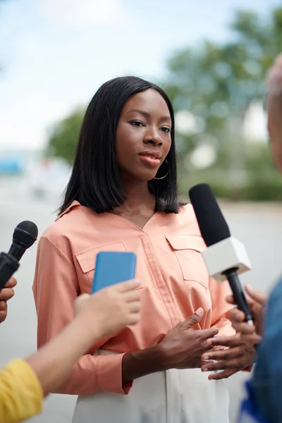 Portrait of Black elegant woman talking to journalists outdoors