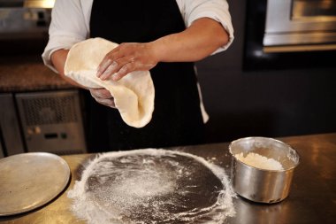 Pizzacının tepsiye hamur koyarkenki görüntüsü