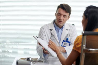 Estetik cerrah müşteriyle konuşuyor. Sağlık sigortası detaylarını anlatıyor.