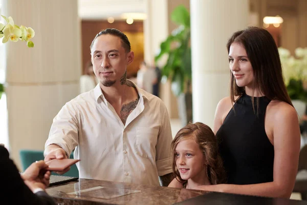 Family with kid giving passports to hotel receptionist