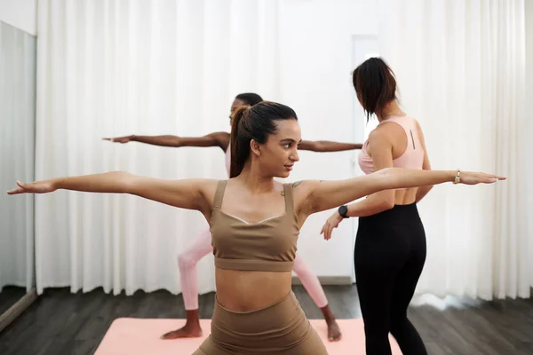 年轻女子和朋友一起上瑜伽课时摆姿势 — 图库照片