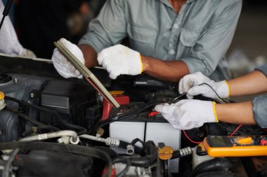 Araba motoru incelenirken dijital endoskop ve tablet bilgisayar kullanan araba tamircileri