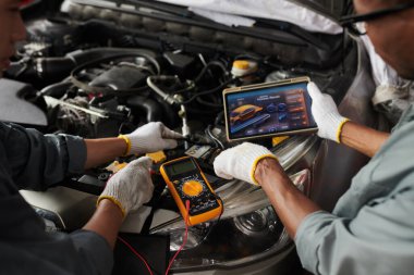 Otomobil motorlarını kontrol ederken uygulamayı tablet bilgisayarında kullanan mekaniklerin yakın plan resmi