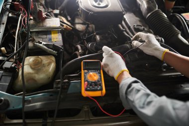 Araba servisi çalışanı, araba motoru kontrol edilirken çokölçer kullanır