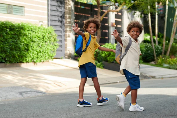 快乐的孩子们在离家和上学的路上挥动着他们的父母 — 图库照片