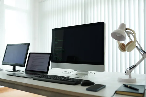 公司办公室屏幕上有程序代码的计算机和笔记本电脑 — 图库照片