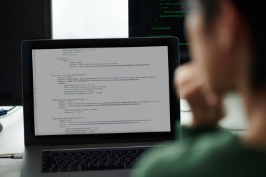 Dizüstü ve bilgisayar ekranlarındaki programlama kodlarına bakan Devops mühendisi