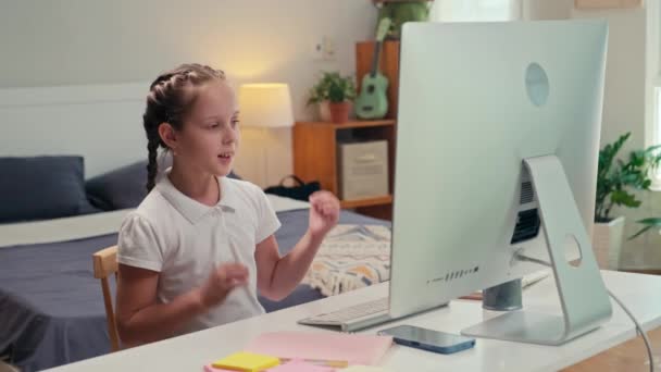 コンピュータモニターの前に座って 自宅でオンラインクラスを持つときに彼女のチューターとビデオ会議で話す14歳の少女 — ストック動画