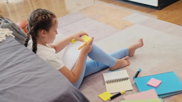 Kleines Mädchen Das Etwas Auf Aufkleber Schreibt Während Kinderzimmer Hausaufgaben — Stockvideo
