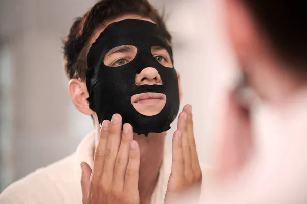 Jongeman Met Zwarte Hydraterende Laken Masker Zijn Gezicht Staan Voor — Stockfoto