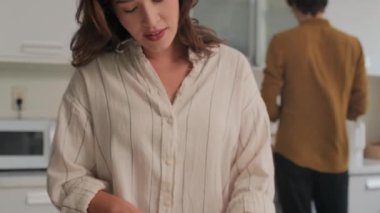 Genç bir kadının kocasıyla konuşurken, salata için sebze keserken, birlikte akşam yemeği hazırlarken,