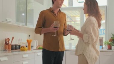 Genç çiftin yemekten önce mutfakta dikilirken şarapla ve dansla vakit geçirdiği orta boy bir fotoğraf.