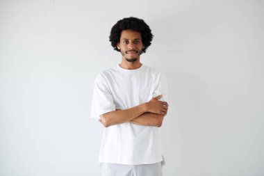 Gülümseyen, kendinden emin, kolları bağlı genç siyahi bir adamın portresi.