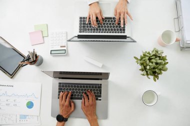 Starupper 'lar satış verilerini ve ziyaretçi etkinliklerini incelerken dizüstü bilgisayarlarda çalışırken, yukarıdan görünüm